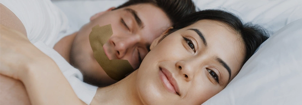 A couple sleeping with the man wearing anti snore patch